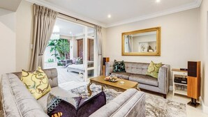 A living room with a sofa, coffee table, and a large mirror. - Luxurious & Spacious Home in the heart of Sandton (Sandton)