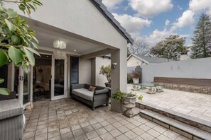 Eine Terrasse mit einer Couch, einer Bank und Topfpflanzen.