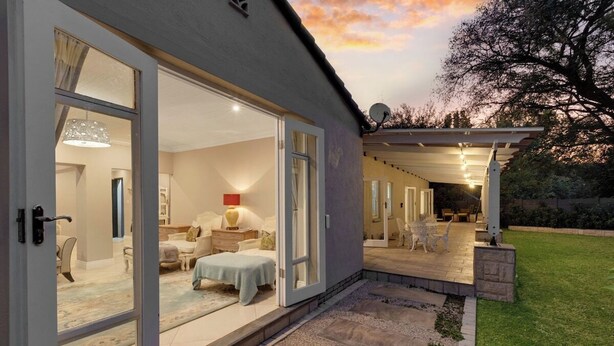 A modern house with a patio, a dining area, and a bedroom with a large window. - Luxurious & Spacious Home in the heart of Sandton (Sandton)