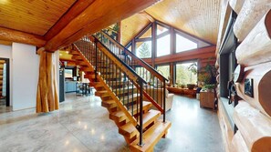 A spacious interior with a wooden staircase, large windows, and a cozy seating area.
