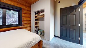 A bedroom with a bed, a window, a closet, and a door.