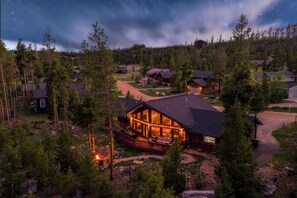 A lodge with a deck, surrounded by trees, under a starry sky. - Family retreat + Game Room, Fire Pit & Views | Near RMNP+ Grand Lake (Grand Lake)