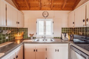 Eine Küche mit Holzausstattung, einer doppelten Spüle, einer Uhr und einem Fenster.