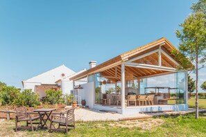 A modern house with a glass-enclosed patio, outdoor furniture, and a white exterior.