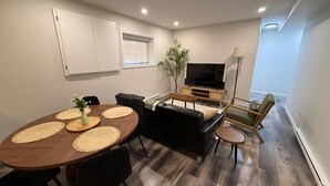 Een moderne woonkamer met een eettafel, banken, een televisie en een plant.