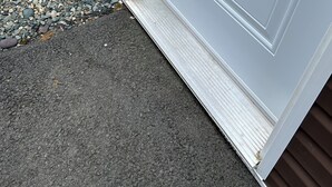 Een witte deur met een metalen hendel en een klein raam erboven.