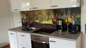 Une cuisine moderne avec des meubles blancs, une cuisinière en acier inoxydable et un revêtement mural décoré de motifs inspirés de la nature.