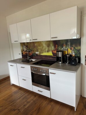 Eine moderne Küche mit weißen Schränken, einem Edelstahlherd und einer Spritzschutzwand mit einem Naturmotiv.