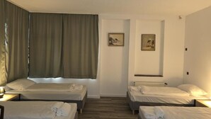 Habitación de hotel con dos camas, una ventana con cortinas y dos cuadros en la pared.