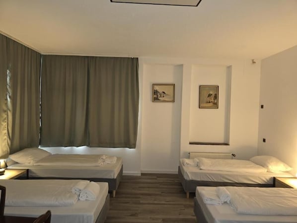 Habitación de hotel con dos camas, una ventana con cortinas y dos cuadros en la pared.