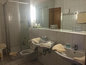 Un baño con dos lavamanos, un inodoro, una ducha y un espejo.