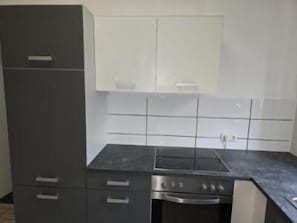 Una cocina con estufa, horno y alacenas.