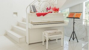Ett piano i en modern, vit inredd miljö med en spiraltrappa och ett notställ med noter.