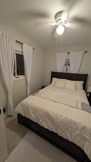 A bedroom with a bed, a ceiling fan, and a window with curtains. - All Sports Lakefront Sunset w/Deck, Firepit, Dock (Ortonville)