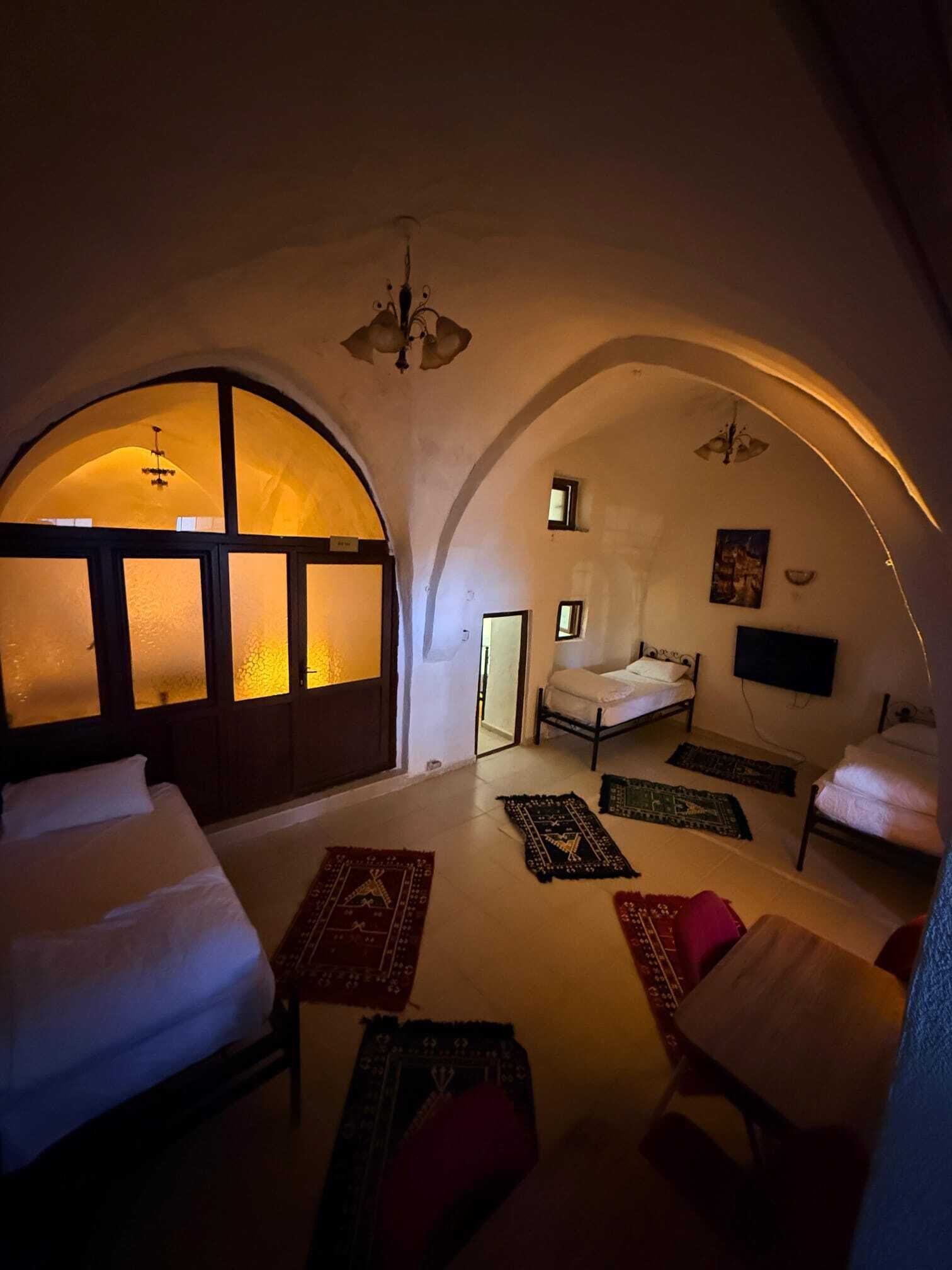 Una habitación con techo abovedado, una cama, un sofá, una mesita y un televisor.