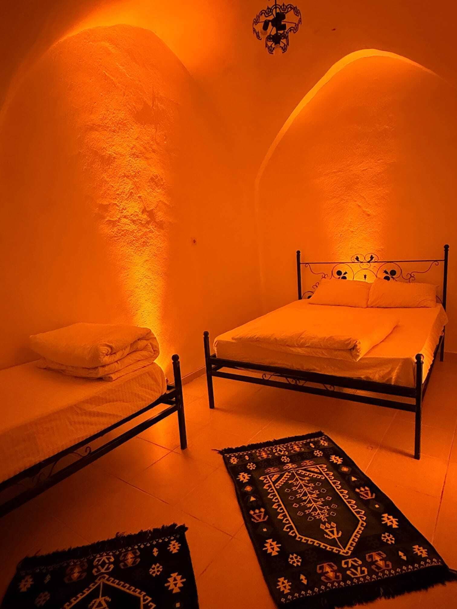 Um quarto com uma cama, uma cama adicional e um tapete estampado.