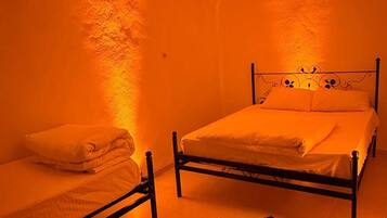 Um quarto com uma cama, uma cama adicional e um tapete estampado.