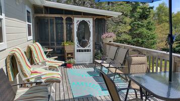 Une terrasse couverte, aménagée avec du mobilier d’extérieur, une table et une plante en pot.