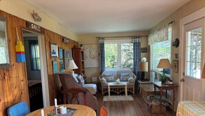 Um quarto aconchegante com uma mesa de jantar de madeira, um sofá, um mapa na parede e uma janela com cortinas.