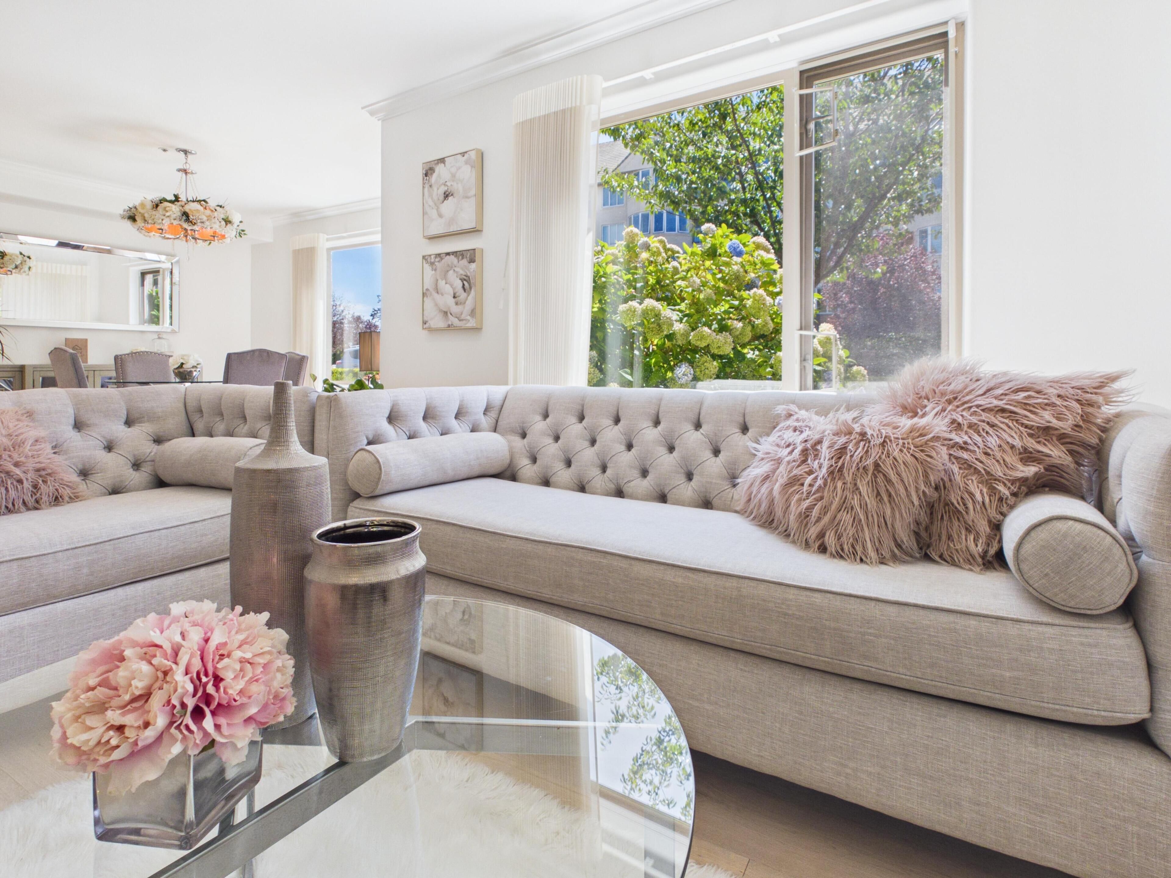 A modern living room with a sectional sofa, a glass coffee table, and a vase with flowers.