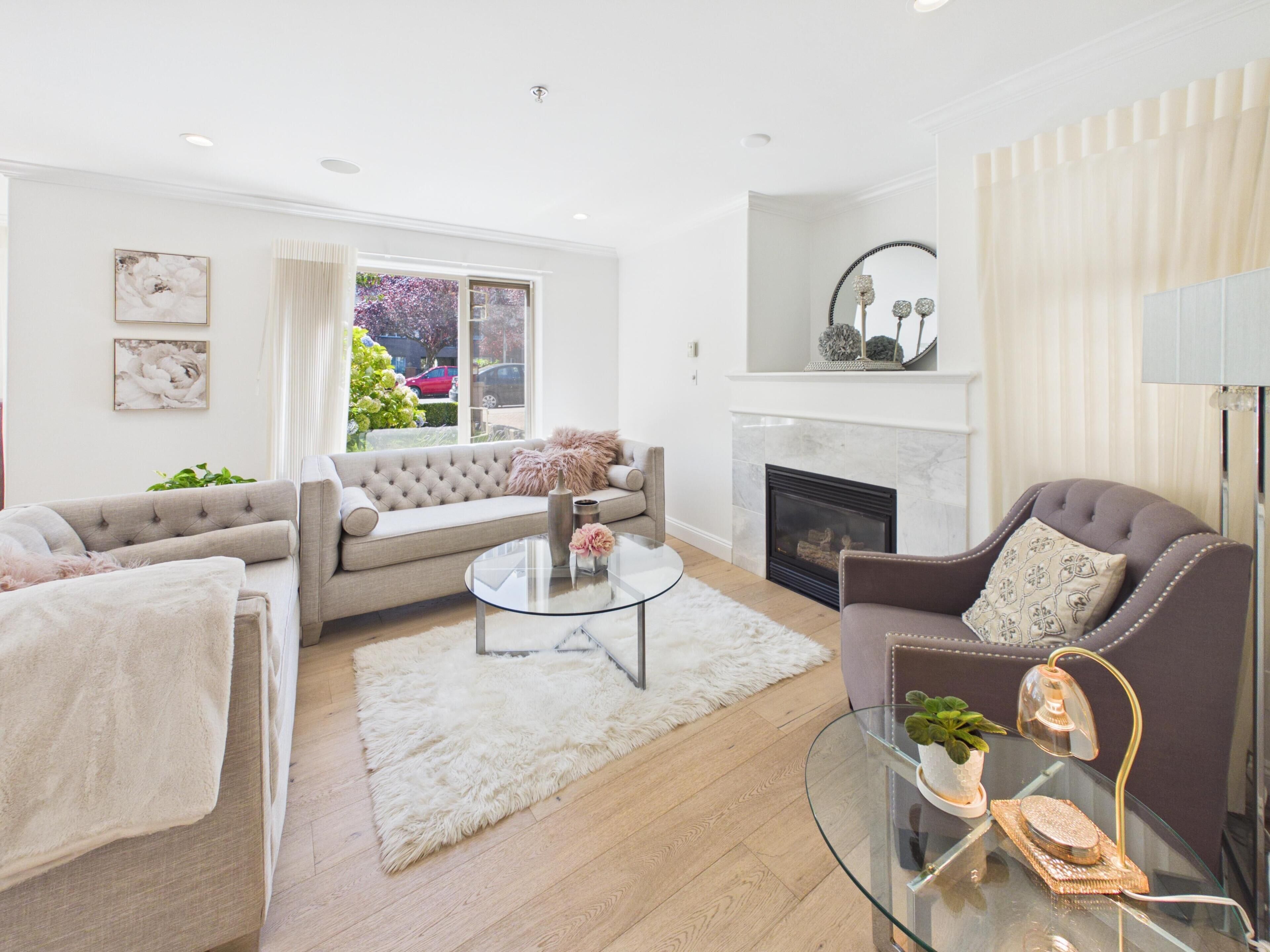 A modern living room with a fireplace, a sofa, a round coffee table, and a glass table with decorative items.