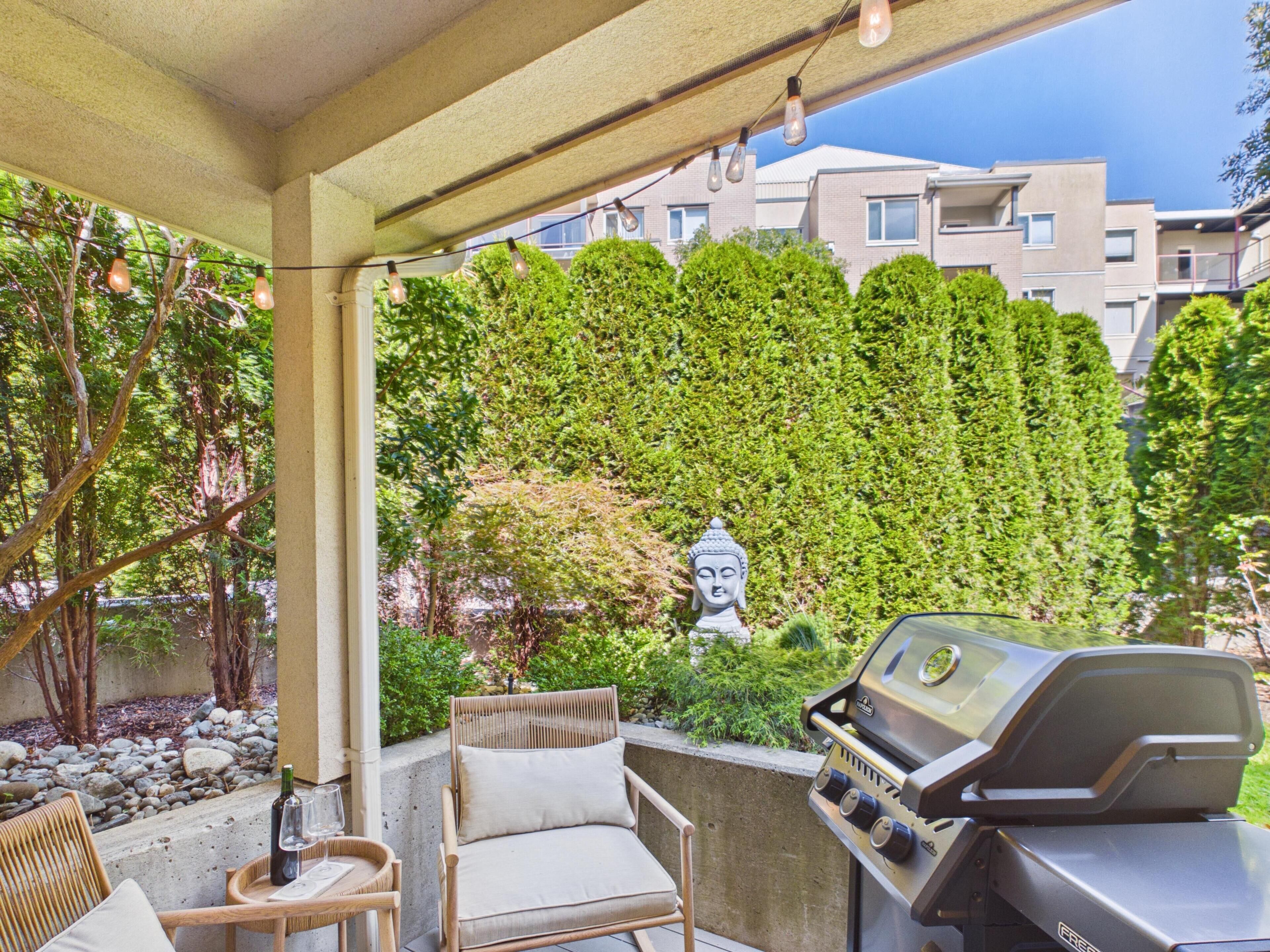 A patio with a grill, seating, and a Buddha statue.