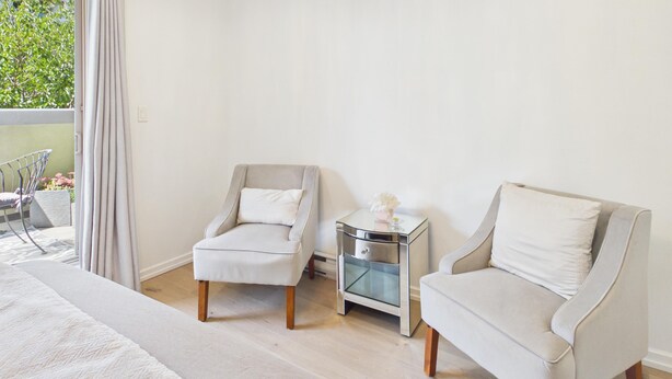 A room with two armchairs, a small bedside table, and a large window with curtains. - Luxury 3BR Townhome with Garden Oasis (Victoria)