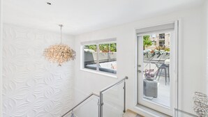A modern interior with a staircase, a decorative wall, and a view of an outdoor seating area. - Luxury 3BR Townhome with Garden Oasis (Victoria)