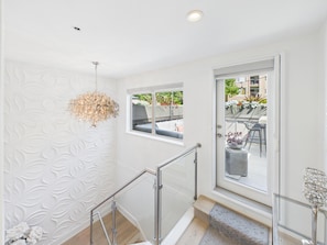 A modern interior with a staircase, a decorative wall, and a view of an outdoor seating area. - Luxury 3BR Townhome with Garden Oasis (Victoria)