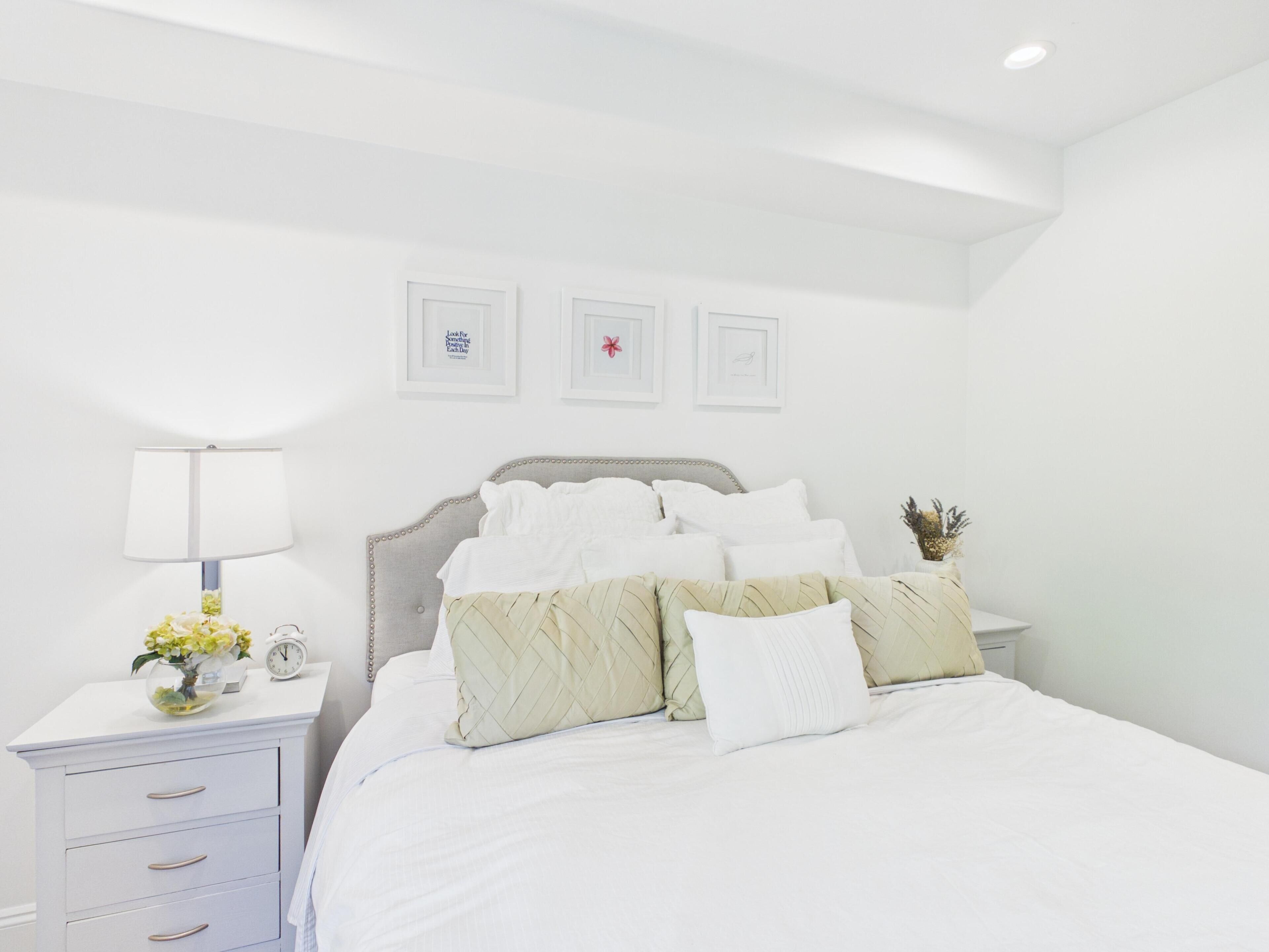 Una camera da letto con un letto, comodini, una lampada e quadri appesi al muro.