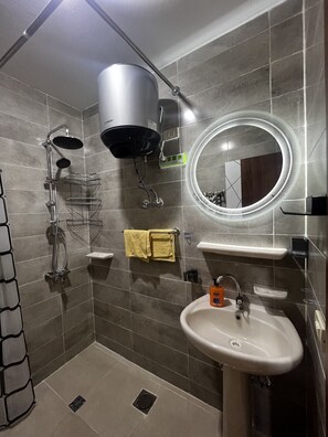 A modern bathroom with a shower, a sink, a mirror, and a towel rack. - Hurghada Tiba Golden Resort Apartment Studio Room Ocean Beach Pool 21 (Al-Bahr al-ahmar)