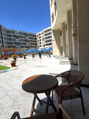 A courtyard with outdoor seating, potted plants, and a building with multiple balconies. - Hurghada Tiba Golden Resort Apartment Studio Room Ocean Beach Pool 21 (Al-Bahr al-ahmar)