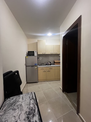 A compact kitchen with a refrigerator, microwave, and wooden cabinets. - Hurghada Tiba Golden Resort Apartment Studio Room Ocean Beach Pool 21 (Al-Bahr al-ahmar)