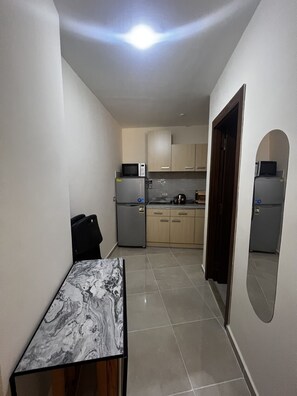 A compact kitchen with a refrigerator, microwave, and stove. - Hurghada Tiba Golden Resort Apartment Studio Room Ocean Beach Pool 21 (Al-Bahr al-ahmar)
