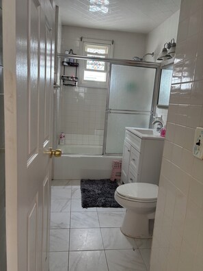 A bathroom with a bathtub, toilet, sink, and a shower area.