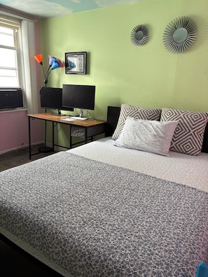 A bedroom with a bed, a desk with a computer, a window with curtains, and wall decorations. - Cozy 1-bedroom house in Queens Village with nearby public transportation (Queens village)