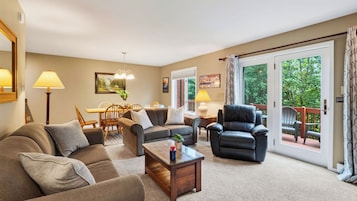 A spacious living room with a sofa, armchairs, a coffee table, and a dining area with chairs and a table.