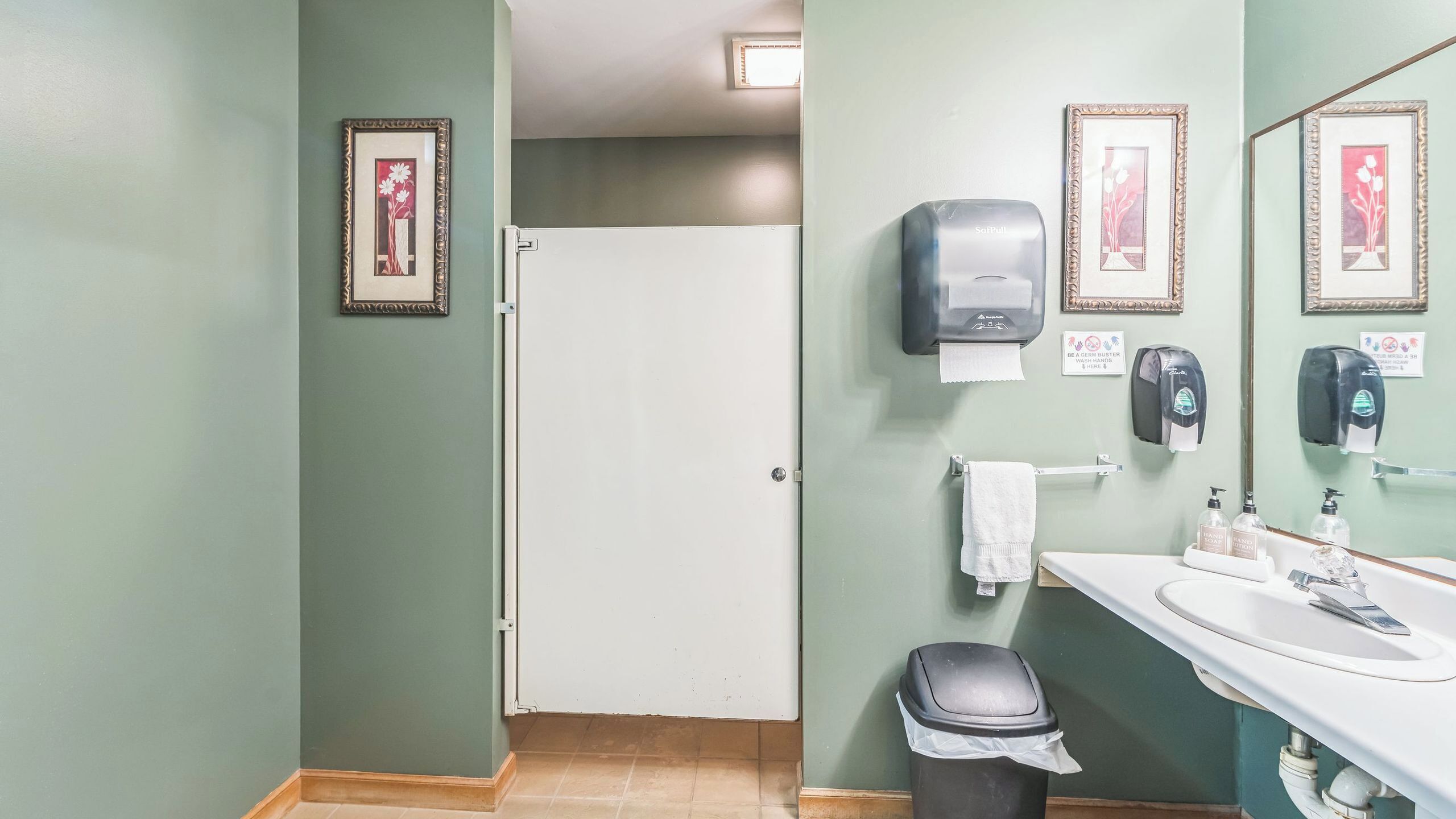 Ein Badezimmer mit Waschbecken, Seifenspender, Papierhandtuchspender und Mülleimer.