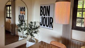 Un comedor con una mesa de madera, un espejo, un cartel que dice 'BON JOUR' y una lámpara colgante.