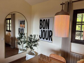 A dining area with a wooden table, a mirror, a 'BON JOUR' sign, and a hanging lamp. - Le Joyau, a gem with magnificent views (Tourtour)