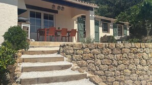 Una casa con una escalera de piedra que conduce a un patio con mobiliario exterior.