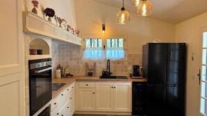 Una cocina con armarios blancos, un refrigerador negro y una ventana con vistas.