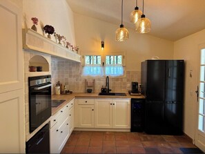 A kitchen with white cabinets, a black refrigerator, and a window with a view. - Le Joyau, a gem with magnificent views (Tourtour)