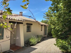 Ein kleines Haus mit Ziegeldach, einem Schotterweg und einem Garten mit verschiedenen Pflanzen.