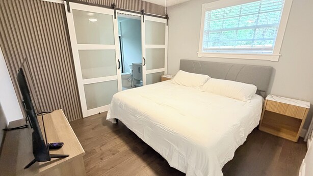 Ein Schlafzimmer mit Bett, Deckenventilator, Fenster mit Jalousien und Schiebetürenschrank.