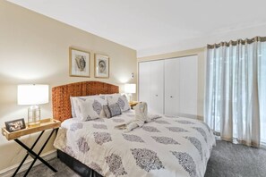 Une chambre d’hôtel avec un lit, une table de chevet, un tableau encadré et une armoire.