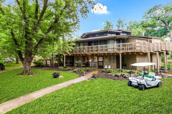 Une maison à deux étages avec un patio couvert et un véhicule de golf stationné dans l’allée.