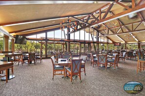 Un vaste espace de restauration intérieur, doté de hauts plafonds et de grandes fenêtres, et comprenant de nombreuses tables et chaises.