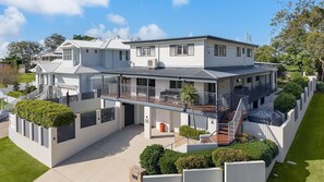 Een huis met twee verdiepingen, een balkon, een overdekte patio en een verzorgd gazon.