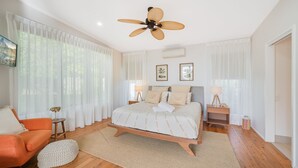 Una camera da letto con un letto, una sedia, un ventilatore a soffitto e un comodino.